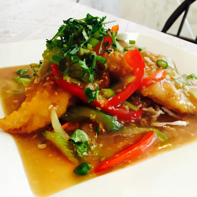 Crispy golden fish fillets with red and green bell peppers, cilantro, and a savory sauce.