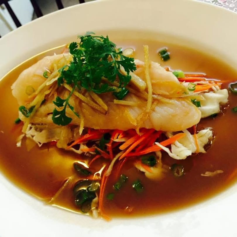Steamed fish with ginger, cilantro, and vegetables in a savory broth, a Thai dish from Tuppee Tong.